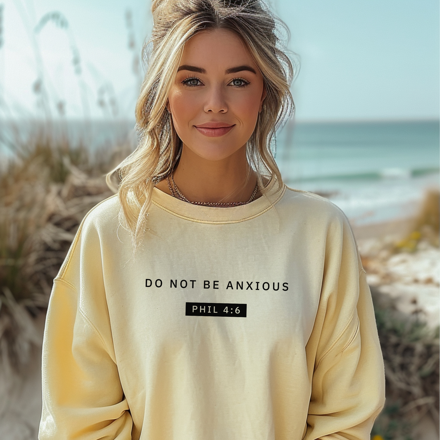 Yellow crewneck sweater with black "Do not be anxious" print. 